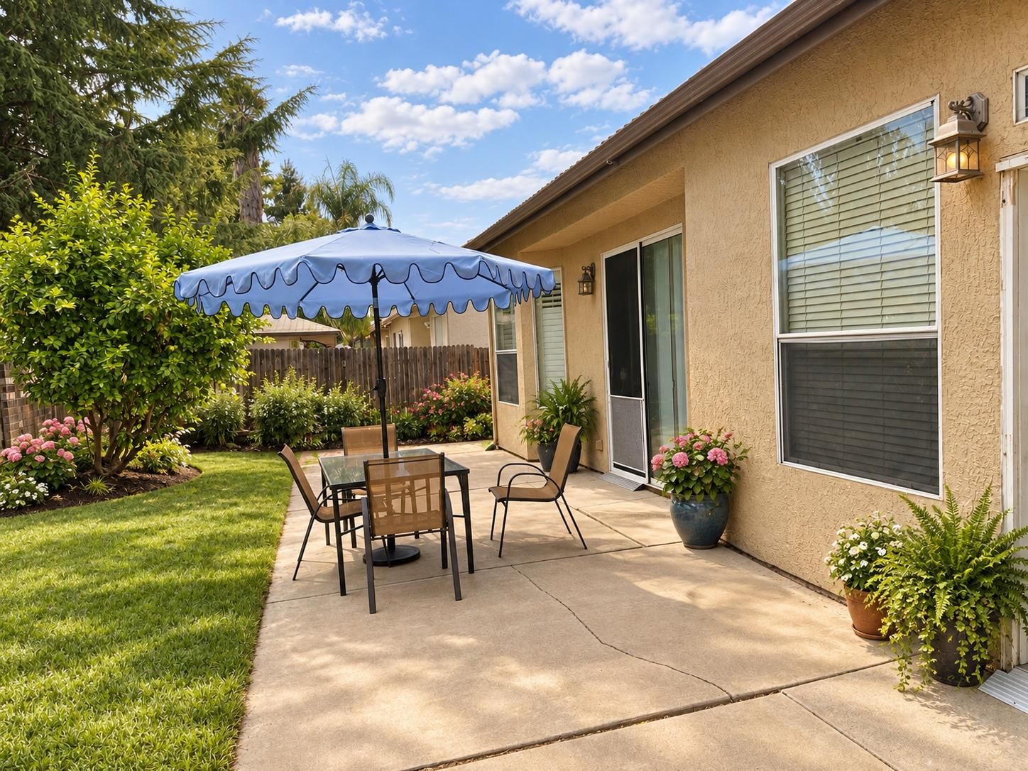 The back patio, with a shaded table, lawn and flowering borders